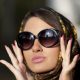 image montrant une femme avec une peau lisse, portant des lunettes de soleil et un foulard dans les cheveux.