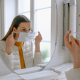 Femme qui met un masque chirurgical sur son visage devant un miroir